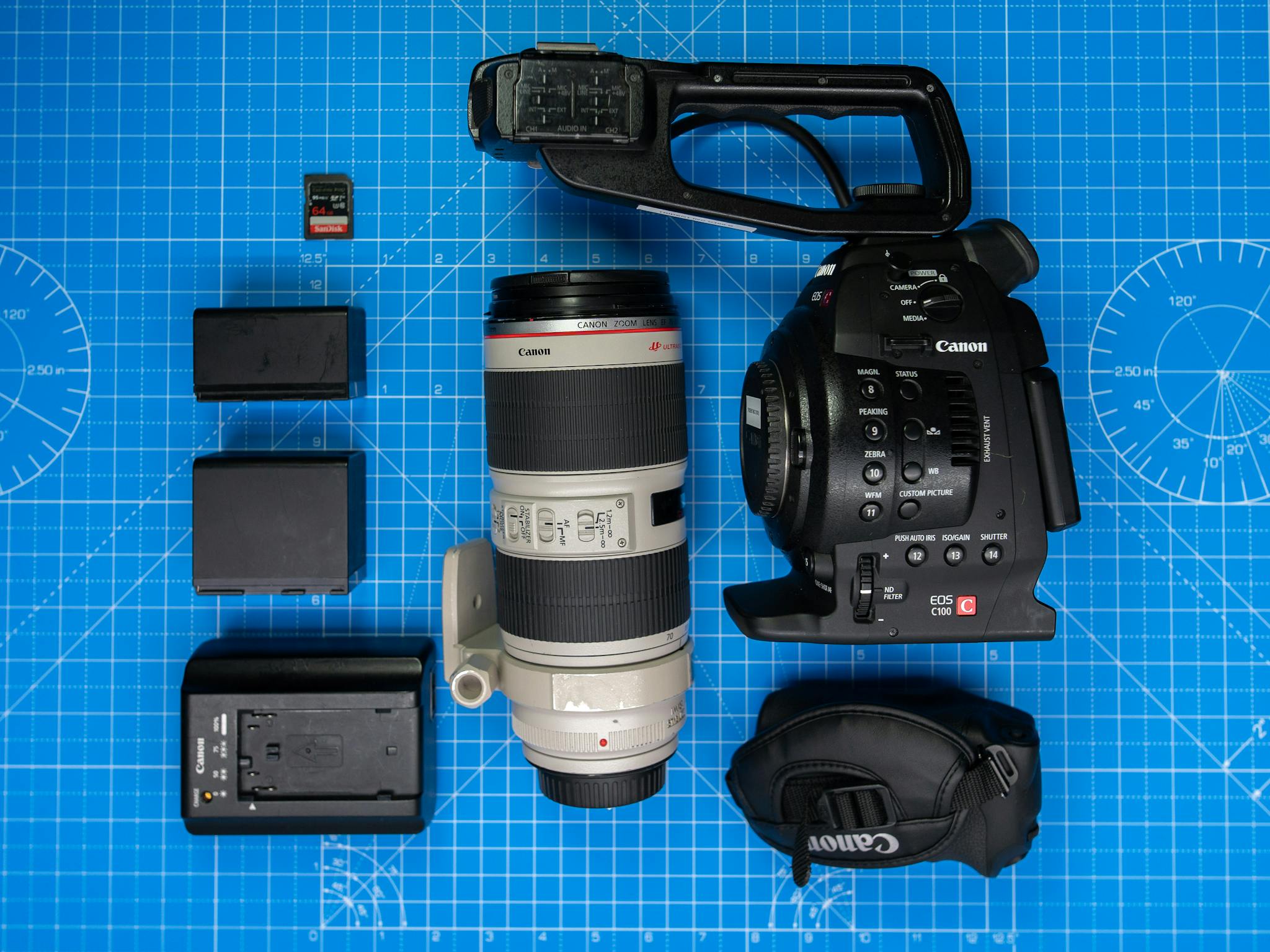 Flat lay of professional camera equipment with lenses and accessories on a blueprint background.