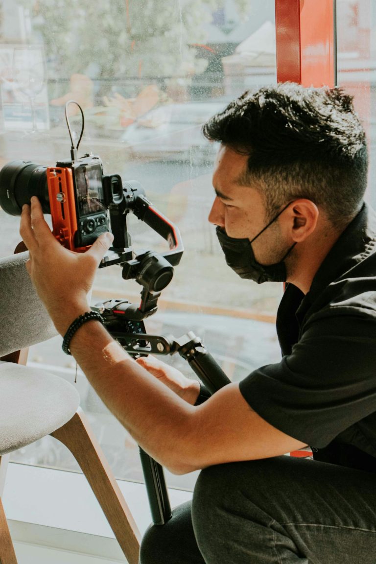 Photographer wearing face mask using camera equipment indoors for filming or photography work.